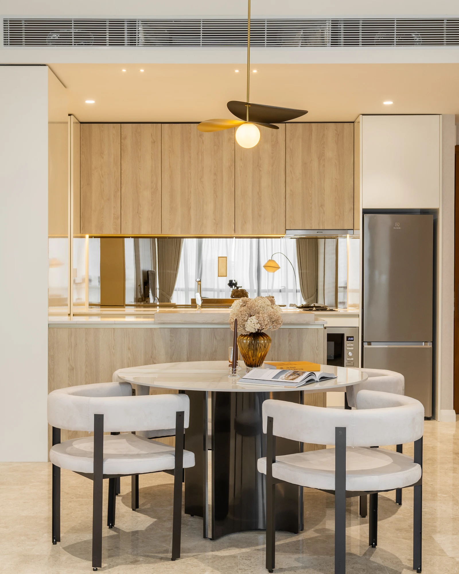 Modern dining area in Kuala Lumpur with reflective wall panels, walnut dining table and stone surfaces