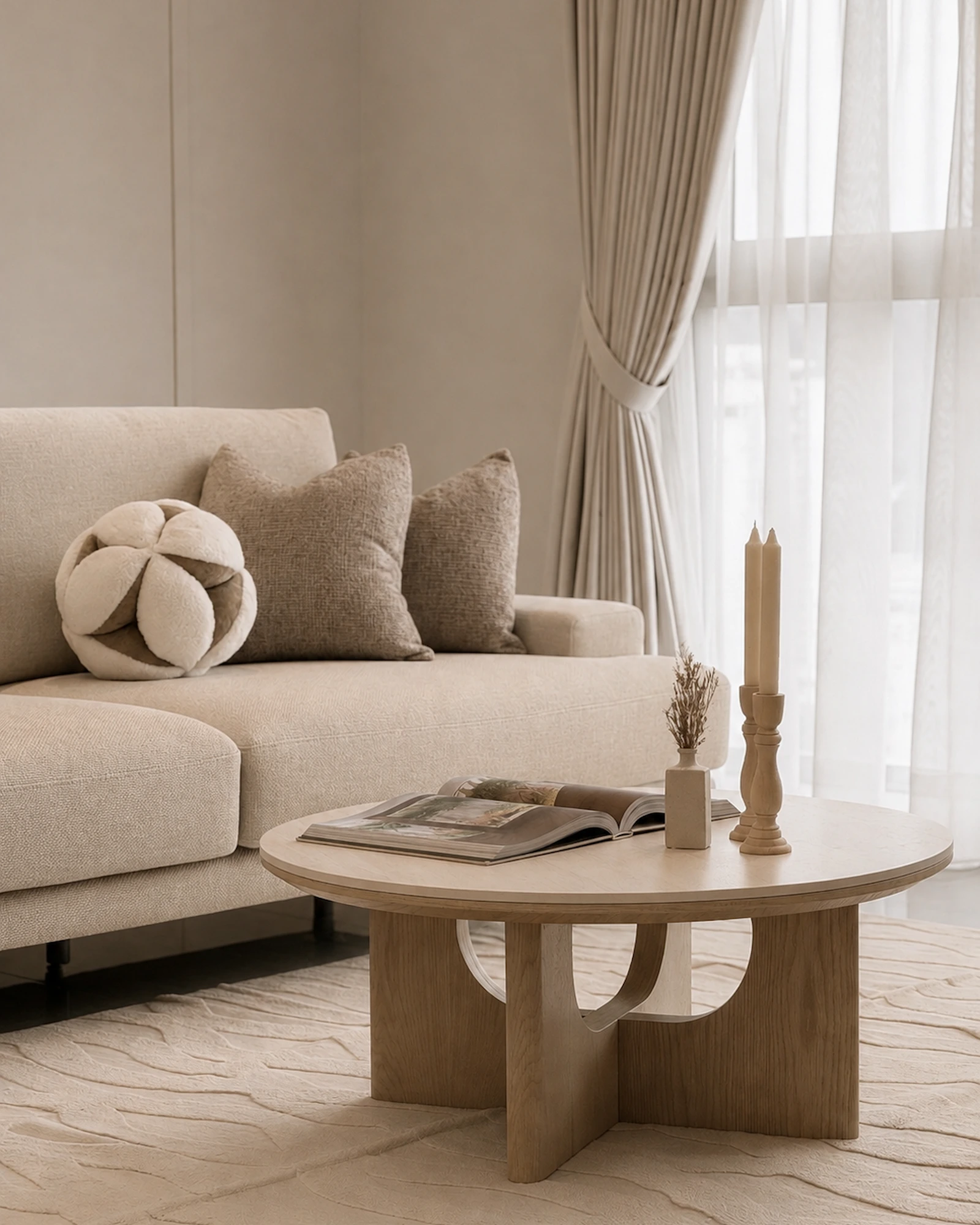 Round wood coffee table with sculptural base, neutral sofa and textured rug in a living room at Ooak Suites, Mont Kiara