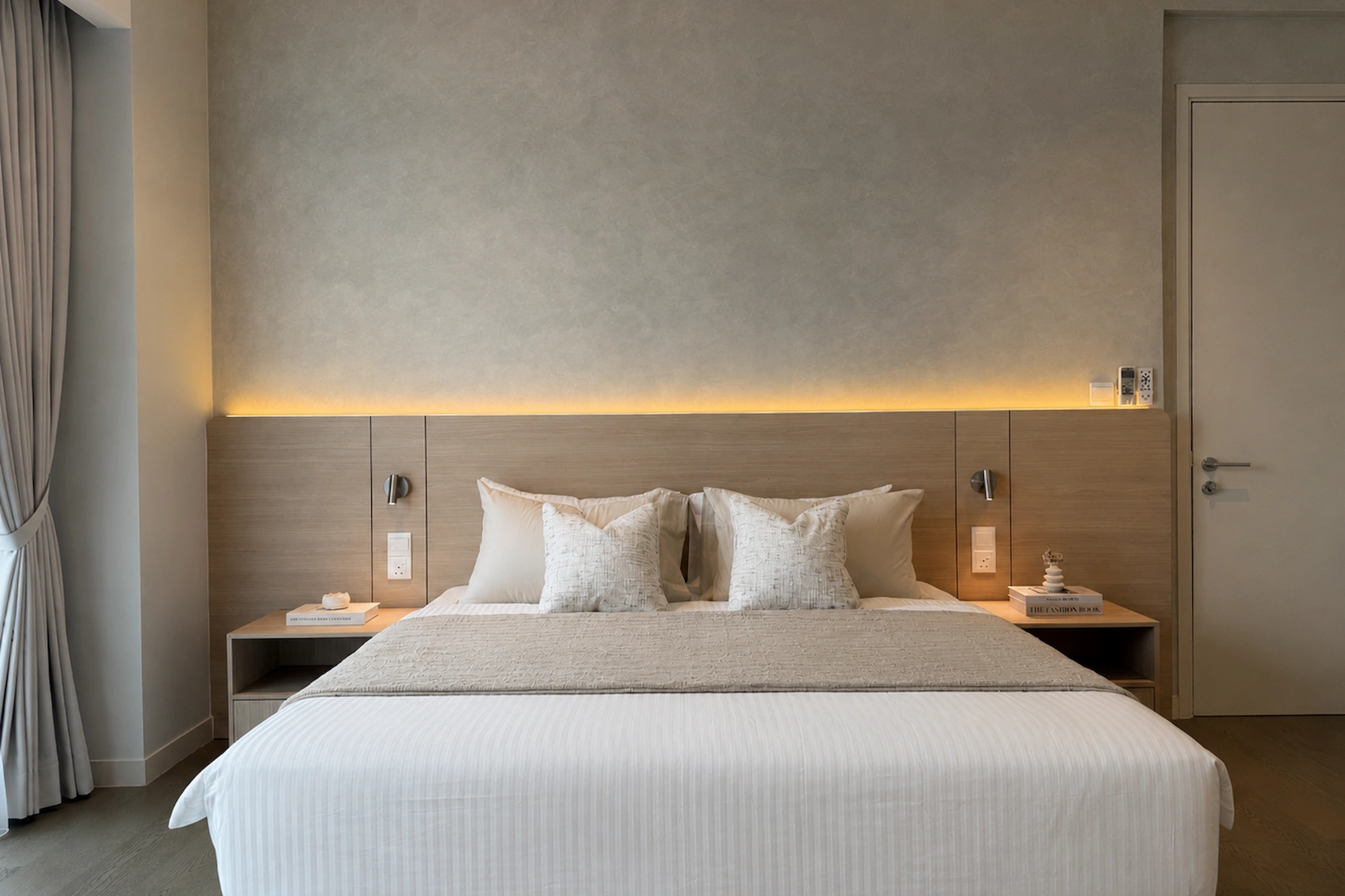 Master bedroom at Ooak Suites, Mont Kiara with a full-width wood headboard, neutral bedding and soft textured finishes