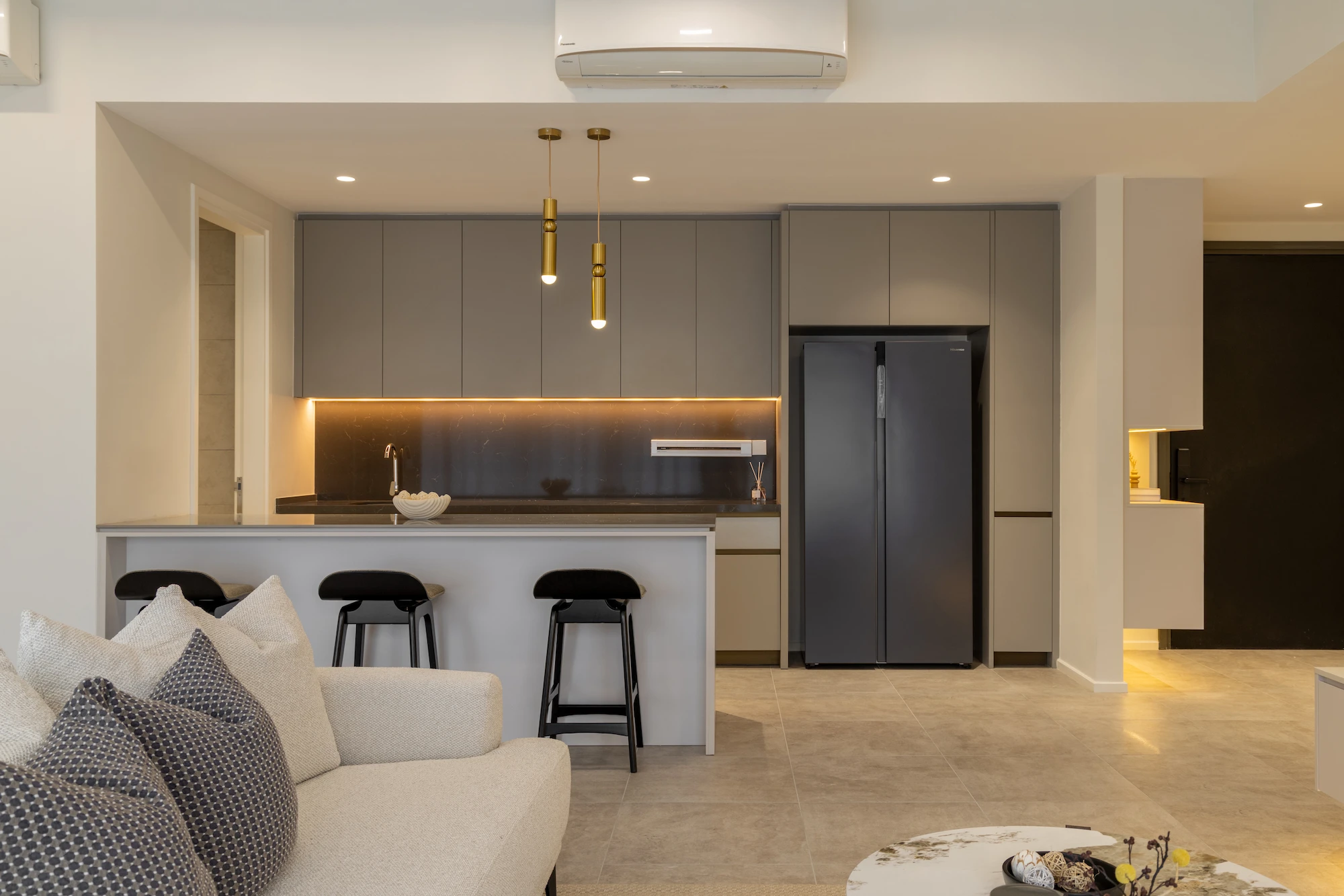 Modern kitchen interior design in Allevia Mont Kiara condominium, Kuala Lumpur, with dark backsplash, integrated cabinetry, kitchen island and black bar stools.