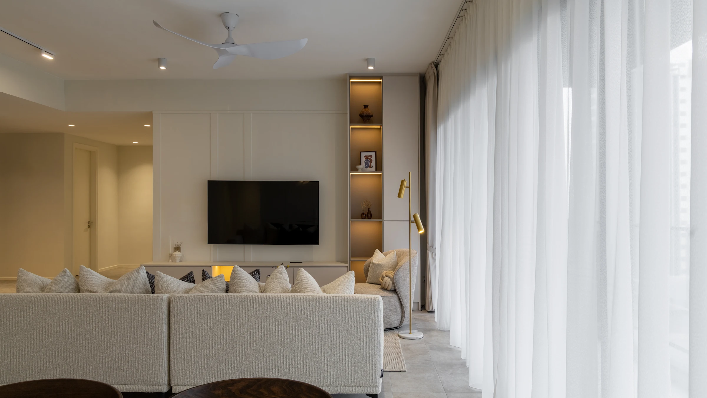 Modern living room interior design in Allevia Mont Kiara condominium, Kuala Lumpur, with custom TV feature wall, built-in shelving and neutral furnishings