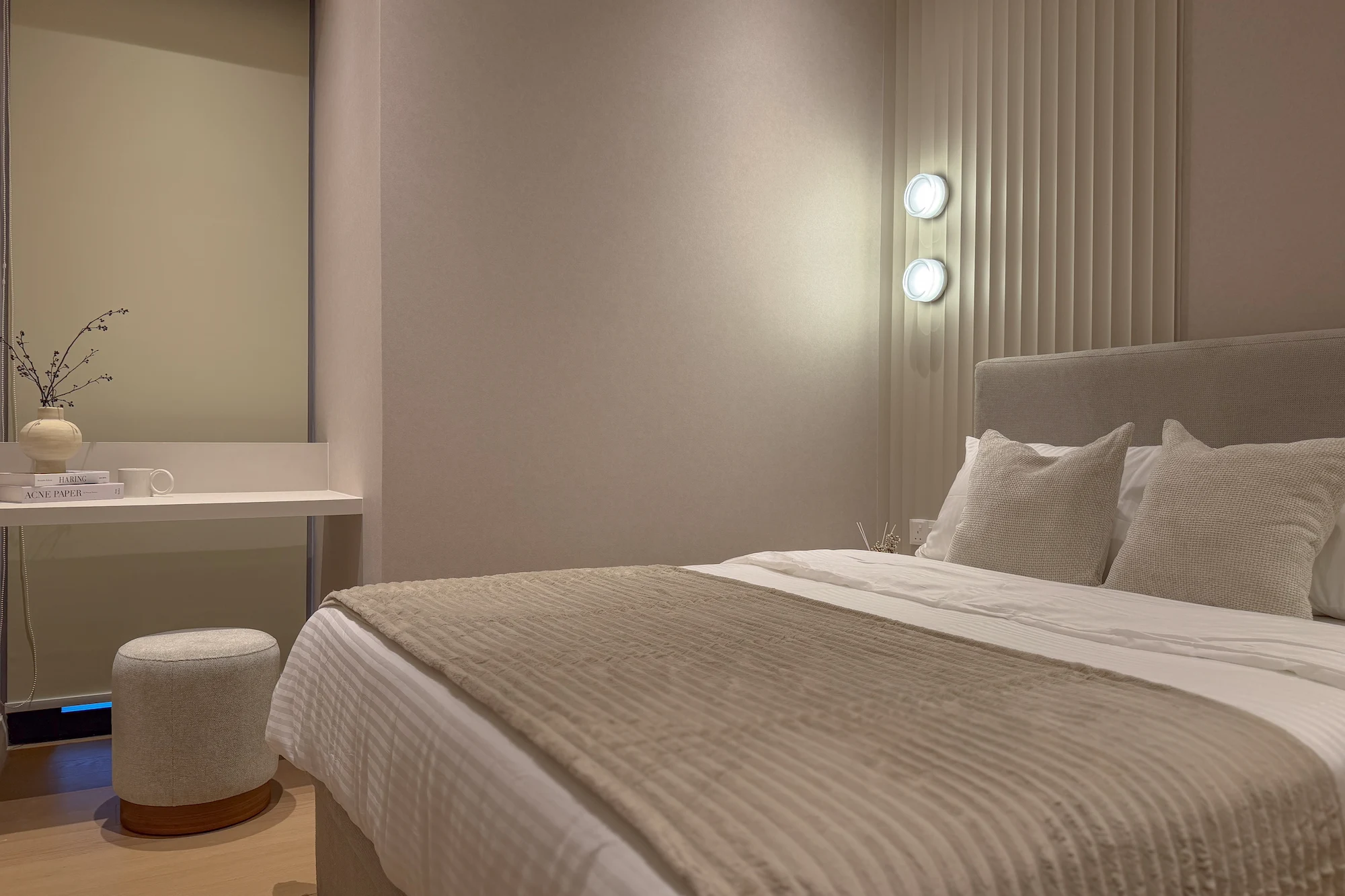 Modern bedroom interior design at TRX Residences, Kuala Lumpur, featuring a textured upholstered headboard, neutral bedding, soft cushions and vertical wall panelling with integrated lighting.