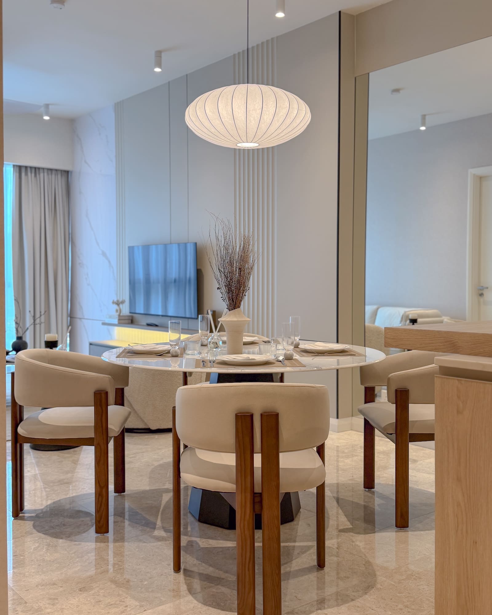 Modern dining room interior design at TRX Residences, Kuala Lumpur, featuring a round dining table, upholstered timber chairs, marble finishes and a large pendant light.