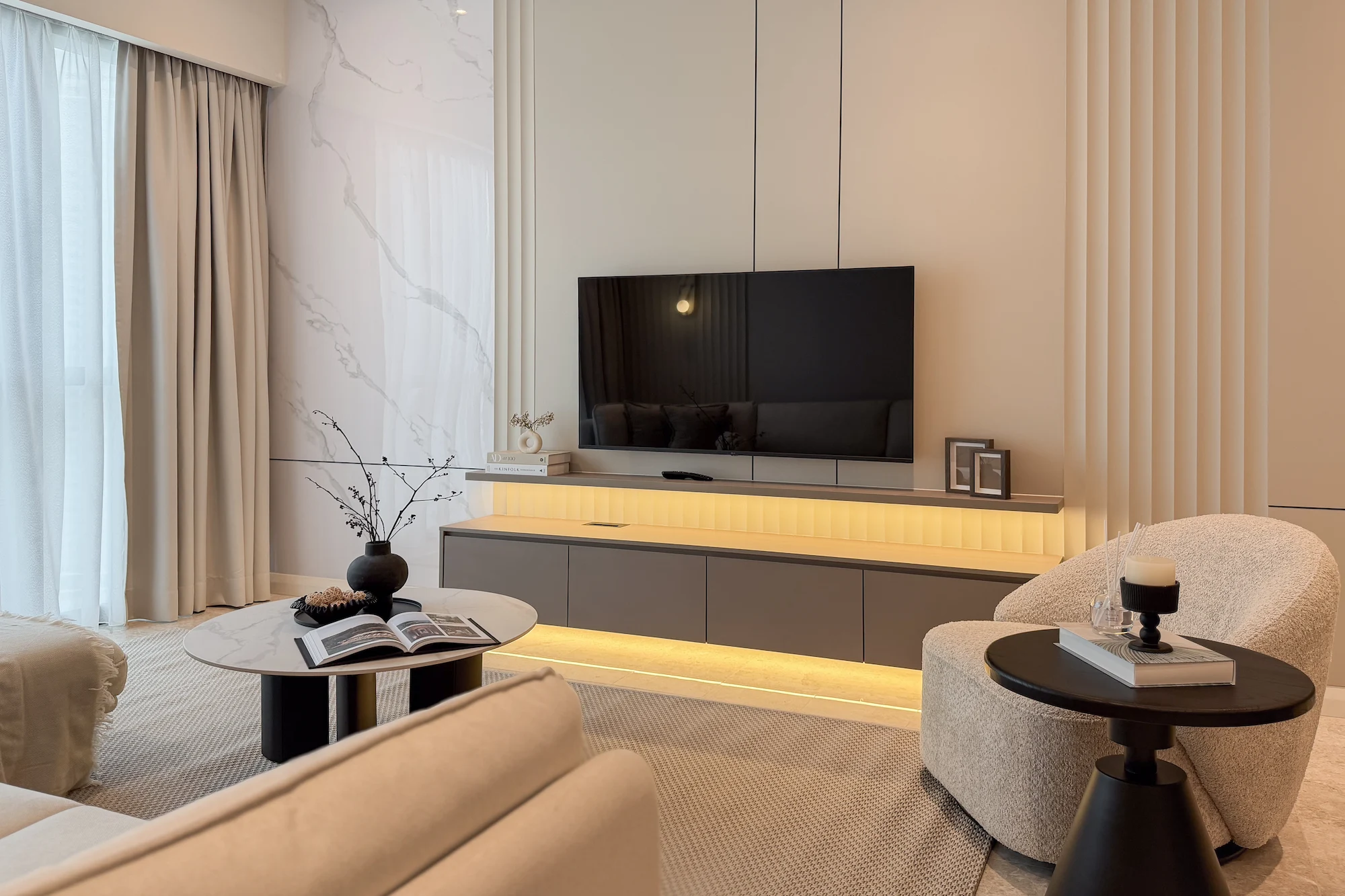 Modern living room interior design at TRX Residences, Kuala Lumpur, featuring a neutral palette, marble feature wall and custom TV console