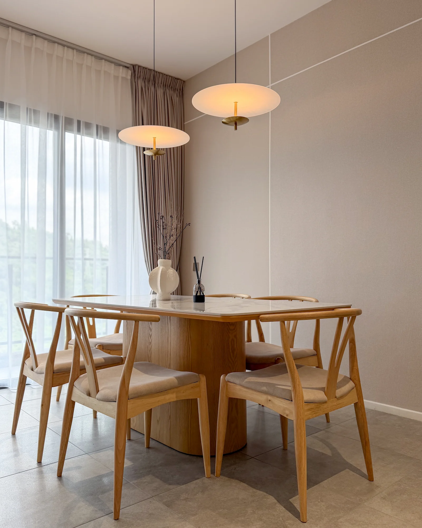 The Muji Apt dining area in Allevia, Kuala Lumpur with a light oak dining table, wooden dining chairs, pendant lights and neutral minimalist interiors.