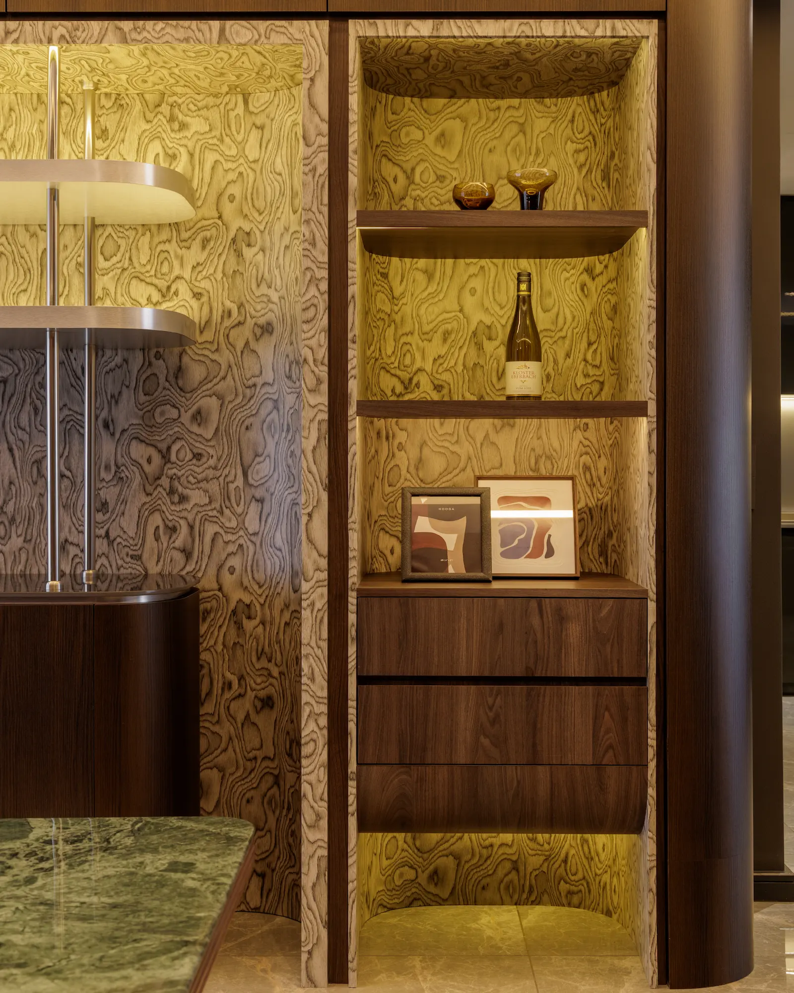 The Radius custom display cabinet featuring illuminated wood-grain panels, open shelving, decorative objects, and integrated storage.