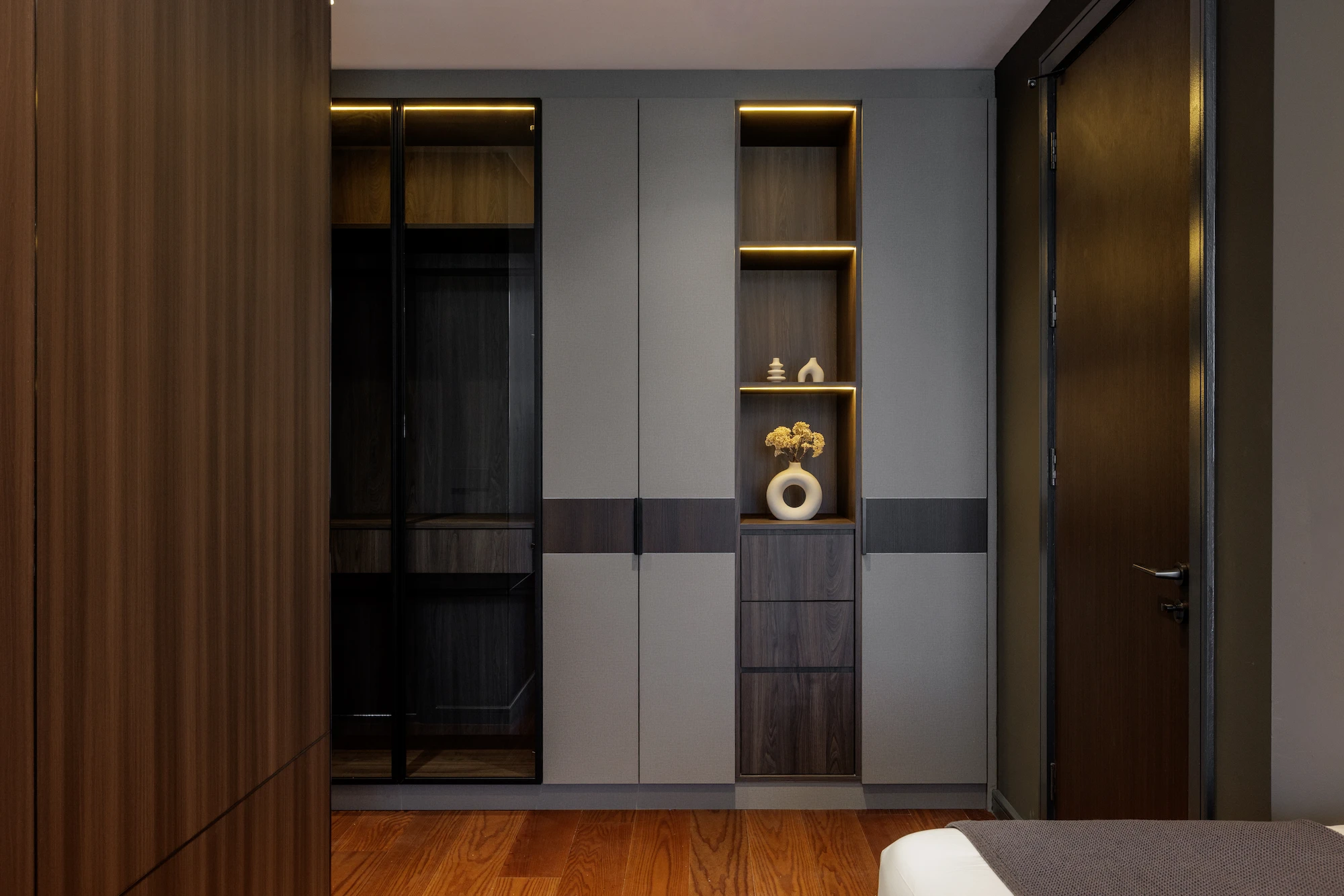 The Radius bedroom featuring built-in wardrobes with illuminated display shelving, dark wood finishes, and integrated storage.