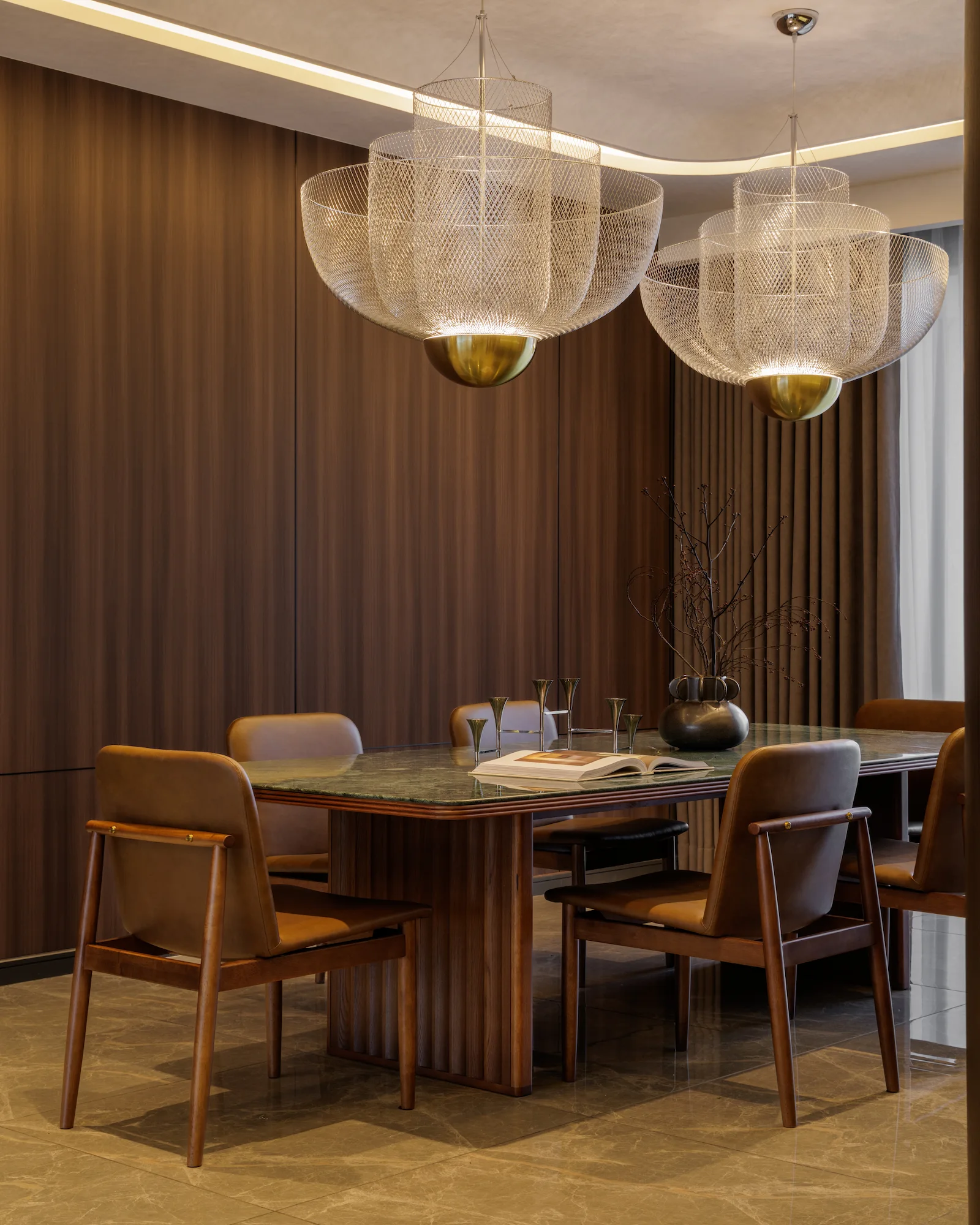 The Radius open-plan dining area featuring a dark wood TV wall, concealed hallway doors, warm marble flooring, and a custom dining area with leather chairs.
