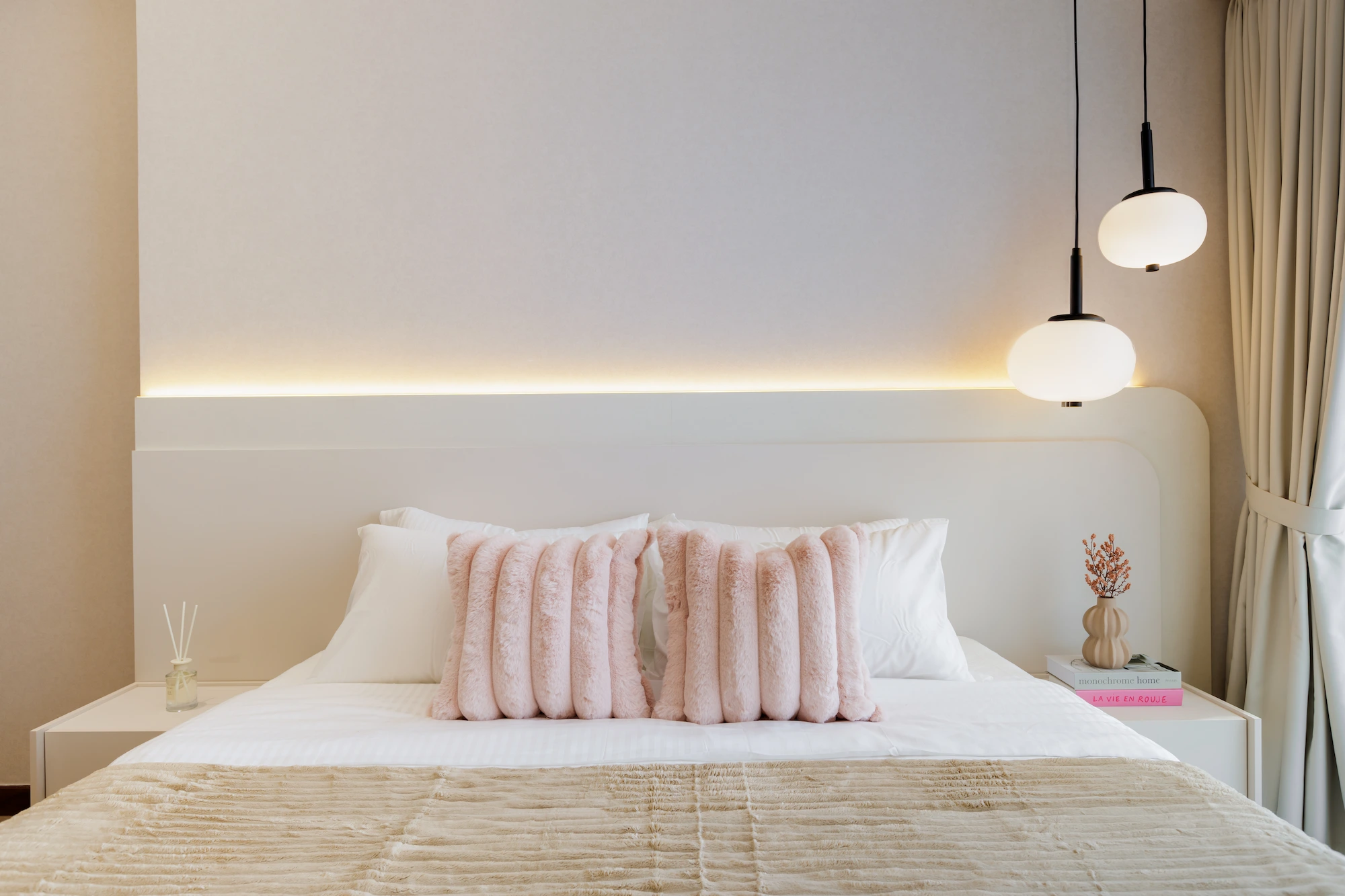 Master bedroom with sculptural upholstered headboard, pendant lights and layered neutral bedding