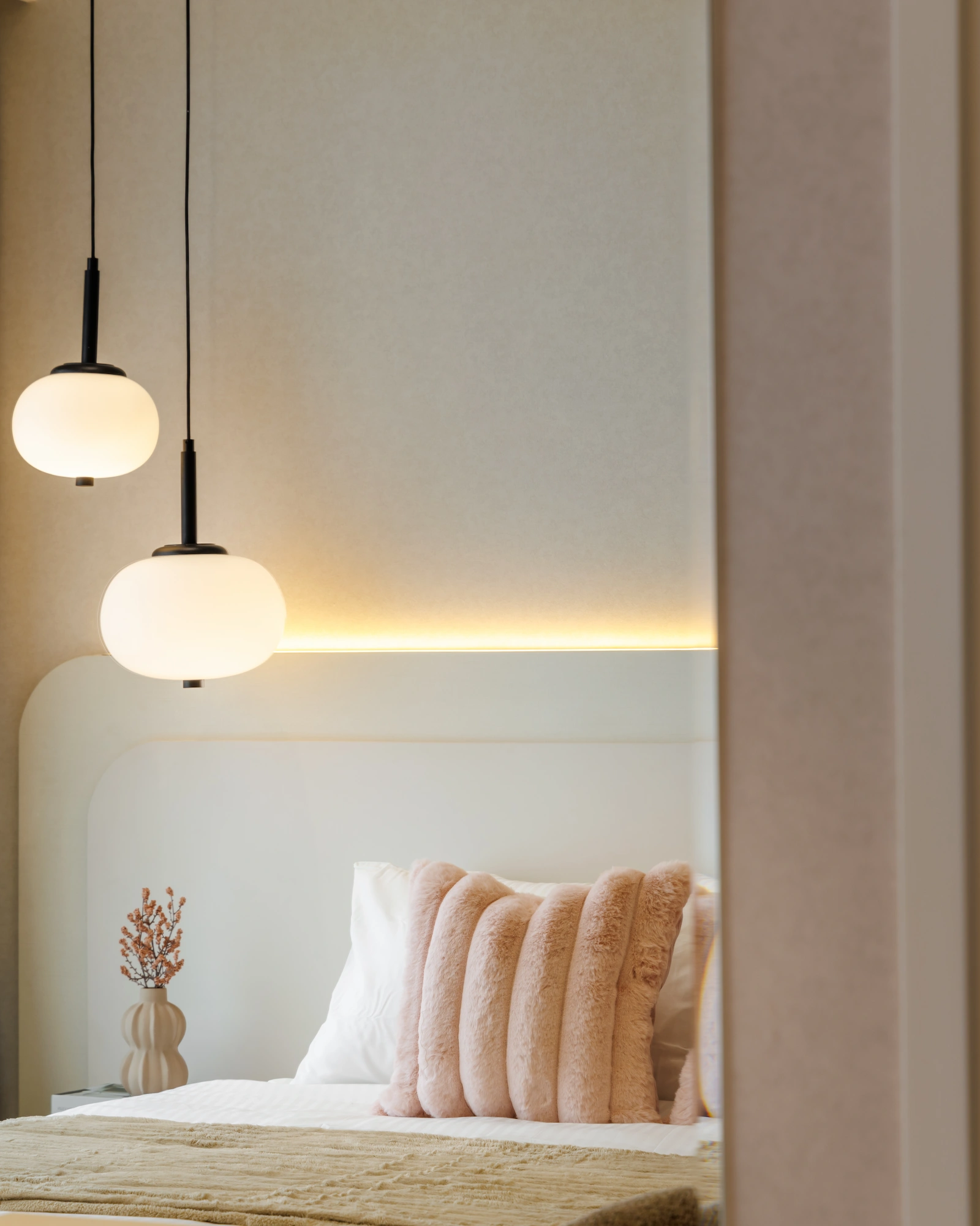 Bedroom reflected in a mirror with globe pendant lights, upholstered headboard and layered bedding